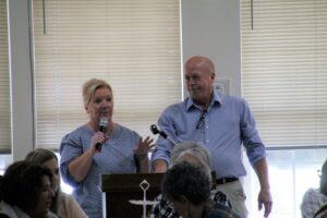 a man and a woman speaking into microphones in front of a group of people